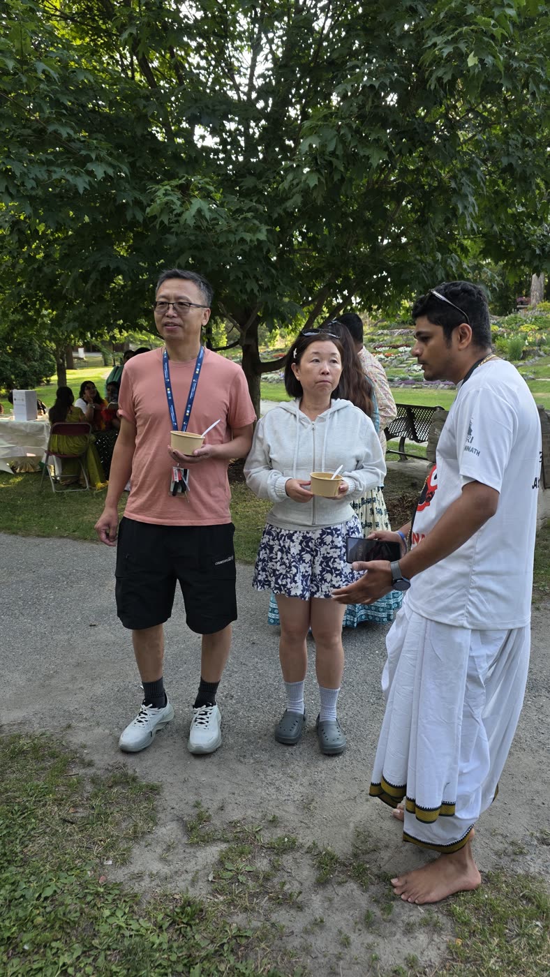 Guests honouring prasādam together in the park