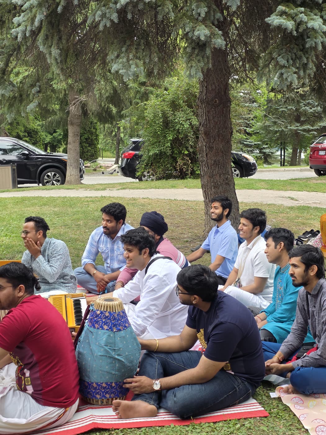 Devotees seated together for kīrtana with mṛdaṅga and karatālas