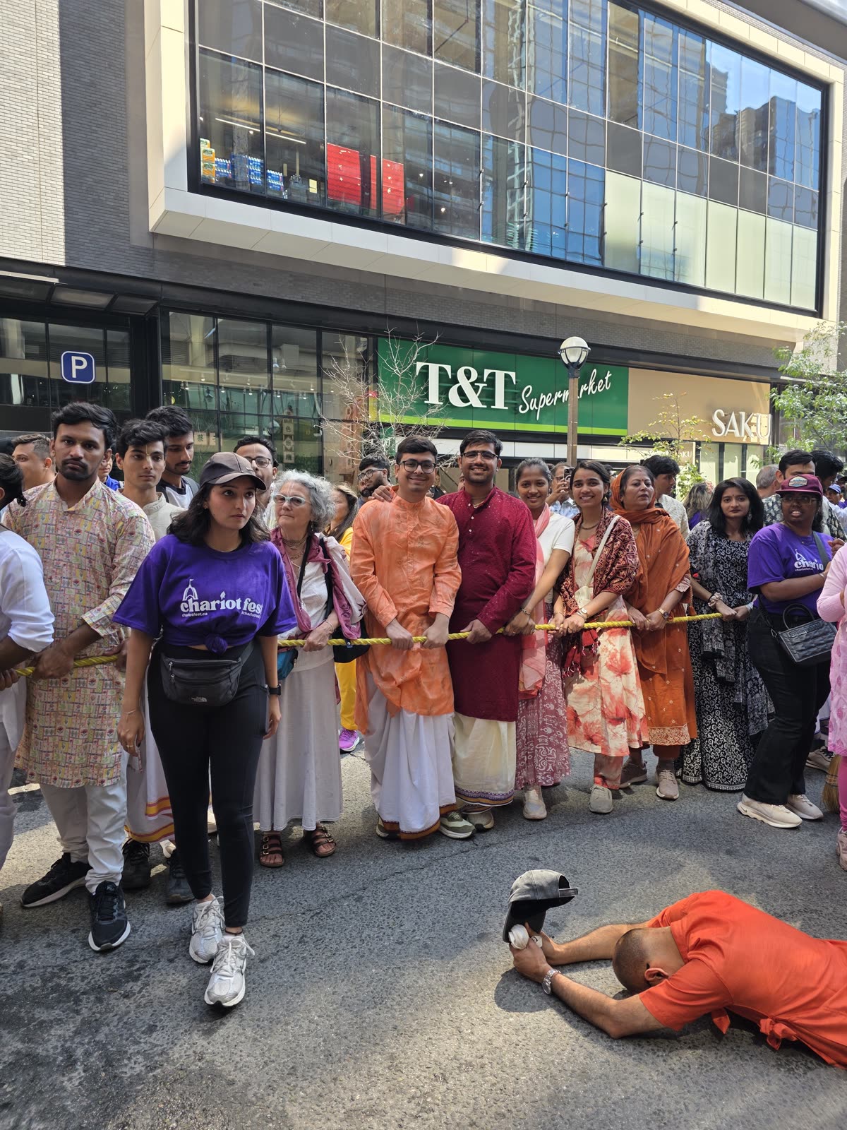 Devotees pulling the chariot rope as one devotee offers obeisances on the road