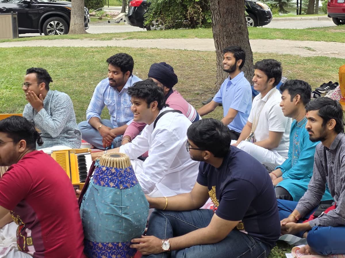 Devotees seated together for kīrtana, chanting the holy names